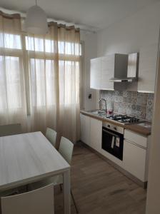 una cocina con armarios blancos y una mesa con sillas. en Casa Giannina, en Palermo