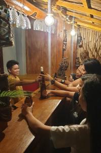un grupo de personas sentadas alrededor de una mesa con botellas de cerveza en CiNta Hotel, en Boracay