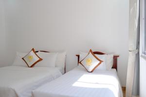 2 letti bianchi posti uno accanto all'altro in una stanza di Tan Son Nhat Con Dao Resort a Con Dao