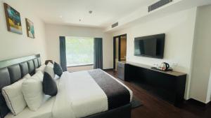 a bedroom with a bed with a television on the wall at Saltstayz Malcha - Chanakyapuri in New Delhi