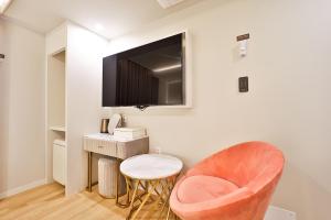 a living room with a chair and a tv on a wall at Den Basta Hotel Hadan in Busan