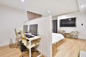 a white room with a desk and a bed and a computer at Den Basta Hotel Hadan in Busan