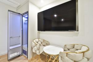 uma sala de estar com duas cadeiras e uma televisão na parede em Den Basta Hotel Hadan em Busan