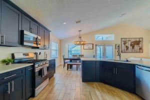 a large kitchen with black cabinets and a table at Spacious Home - Heated LED Pool & Ping Pong in Minneola