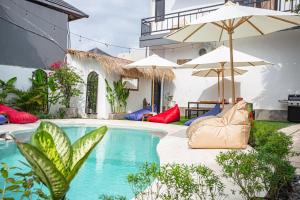 a pool with umbrellas next to a house at What The Duck Backpackers in Canggu