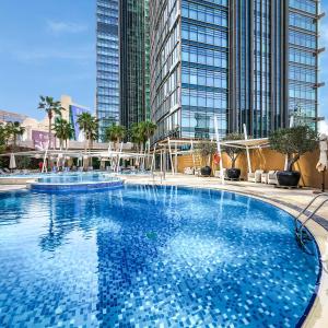a large swimming pool with tall buildings in the background at City Centre Rotana Doha in Doha