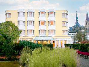 un grand bâtiment jaune avec un jardin en face dans l'établissement Hotel Am Brinkerplatz, à Essen