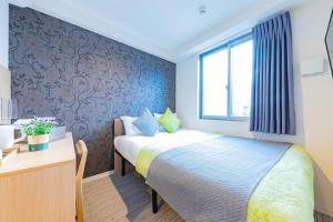 a bedroom with a bed and a desk and a window at JA Hotel Namba-SOUTH難波南 in Osaka
