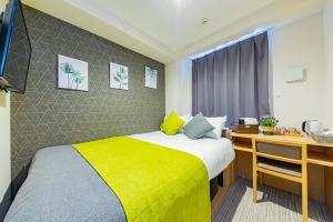 a bedroom with a large bed with a yellow blanket at JA Hotel Namba-SOUTH難波南 in Osaka