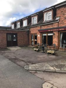 a brick building with tables and chairs in front of it at OYO The Rivenhall Hotel in Witham