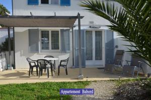 un patio con tavolo e sedie di fronte a una casa di Villa des 4 saisons a Saint-Trojan-les-Bains