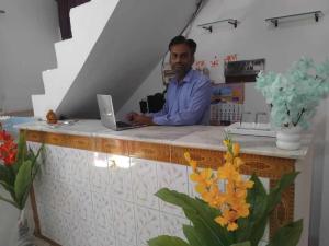 Een man aan een toonbank met een laptop. bij Shivam Hotel & Restaurant in Khajurāho