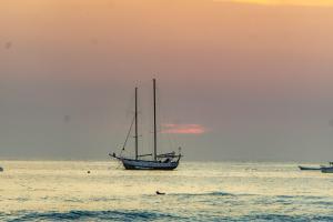 ein Segelboot im Ozean bei Sonnenuntergang in der Unterkunft Casa Nella in Tamarindo