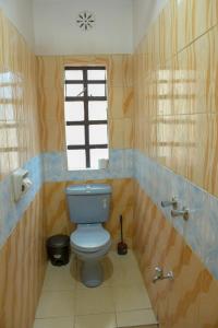 baño con aseo azul y ventana en Effie Homes en Naivasha