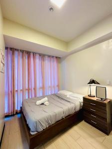 um quarto com uma cama com um candeeiro e uma janela em 8 Newtown Boulevard by Hiverooms em Lapu Lapu City