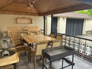 un patio con mesas de madera y sillas en el balcón en Beautiful Guest House Qusar en Qusar