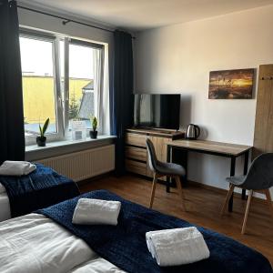 um quarto de hotel com uma cama, uma secretária e uma televisão em Pokoje Gościnne Nad Morzem em Leba