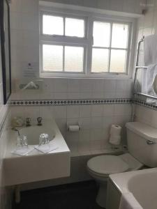 een witte badkamer met een toilet en een wastafel bij OYO The Rivenhall Hotel in Witham