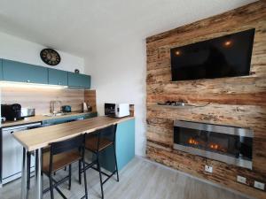 a kitchen with a fireplace and a tv on a wall at Résidence Les Carlines - Studio pour 4 Personnes 664 in Les Orres
