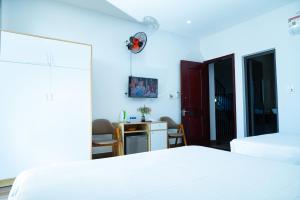 um quarto com uma cama branca e uma secretária em BLUE SEA Motel em Thăng Bình