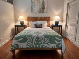 a bedroom with a bed with a green comforter and two lamps at North Shore of Maui - 2bd-2bath in Paia