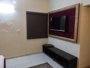 een kamer met een flatscreen-tv aan de muur bij Hotel Shelton in Karachi