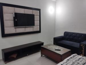 een woonkamer met een bank en een tv aan de muur bij Hotel Shelton in Karachi