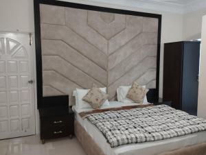 a bedroom with a large bed with a large headboard at Hotel Shelton in Karachi