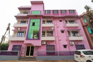 un bâtiment rose avec une voiture garée devant dans l'établissement Goroomgo Hotel Beach Heaven Puri Near Golden Sea Beach & Swargadwar, à Purî