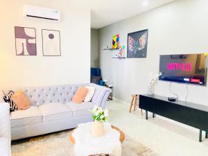 sala de estar con sofá blanco y TV en Luxurious haven retreat en Dar es Salaam