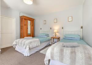a bedroom with two beds and a table with a lamp at Churchtown Cottage in Blisland