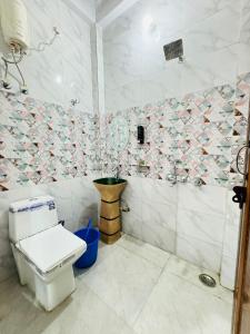 a bathroom with a toilet and a tiled wall at Hotel Sapphire Grand - Onyx Plaza in Ghaziabad