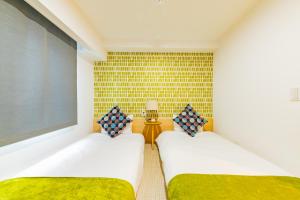 two twin beds in a room with a wall at JA Hotel Midoribashi 綠橋 in Osaka