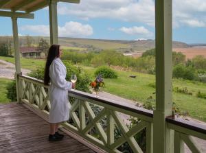 Una donna in piedi su un portico con un bicchiere di vino di Delta Resort Treetop by Eight Continents a Tulcea