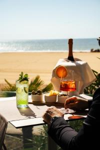 a person sitting at a table near the beach at Hotel Niagara in Lido di Jesolo