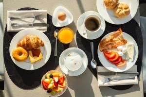 een tafel met borden ontbijtproducten en koffie bij Hotel Niagara in Lido di Jesolo