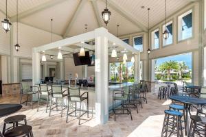 un patio couvert avec des tables et des chaises ainsi qu'un bar dans l'établissement Stunning 5BD Home Private Pool and Spa GAME ROOM, à Kissimmee