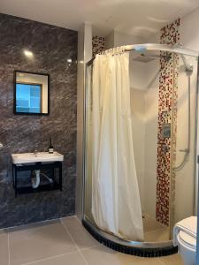 y baño con ducha y lavamanos. en The Pixels Cape Panwa Condo, en Phuket