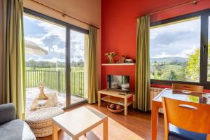 una sala de estar con paredes rojas y una gran ventana. en Almarinae apartamentos, en Castiello de la Marina