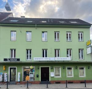 un bâtiment vert et blanc avec un magasin dans l'établissement LIVING Apartments / FeWo Neuwied, à Neuwied