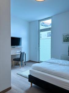 Habitación azul con cama y escritorio con TV. en Pension Töpferhof en Tangermünde
