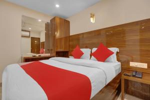 OYO Hotel Royal Park في مومباي: غرفة نوم بسرير كبير ومخدات حمراء