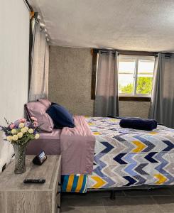 1 dormitorio con 1 cama y un jarrón de flores en Alta Terra Hospedajes, en Quetzaltenango