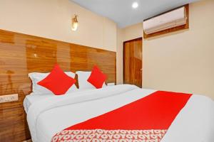 OYO Hotel Royal Park في مومباي: غرفة نوم مع سرير أبيض كبير مع وسائد حمراء