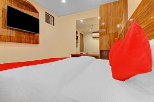 OYO Hotel Royal Park في مومباي: غرفة نوم مع سرير أبيض كبير مع وسائد حمراء