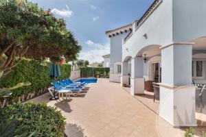 une terrasse avec des chaises bleues et une maison dans l'établissement Mar Menor Golf Resort - 117, à Las Casicas