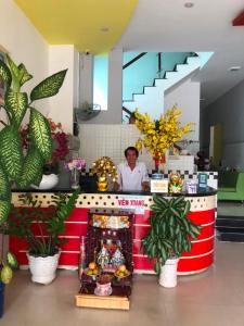 Nam Dương 1 Hotel في فان رانغ: امرأة تقف خلف مكتب مع الزهور والنباتات