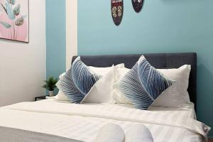 ein Bett mit weißen und blauen Kissen darauf in der Unterkunft Oceanfront Charm 2BR GurneyDrive#SeaviewGeorgetown in George Town