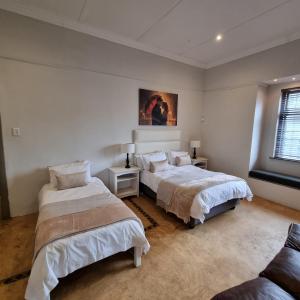 a bedroom with two beds and a couch at Journey Guesthouse in Riversdale