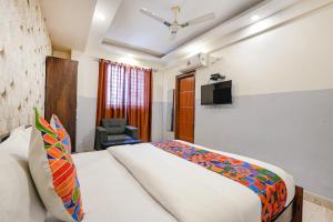 a bedroom with a bed and a chair and a television at FabExpress 24 Plus in Bangalore